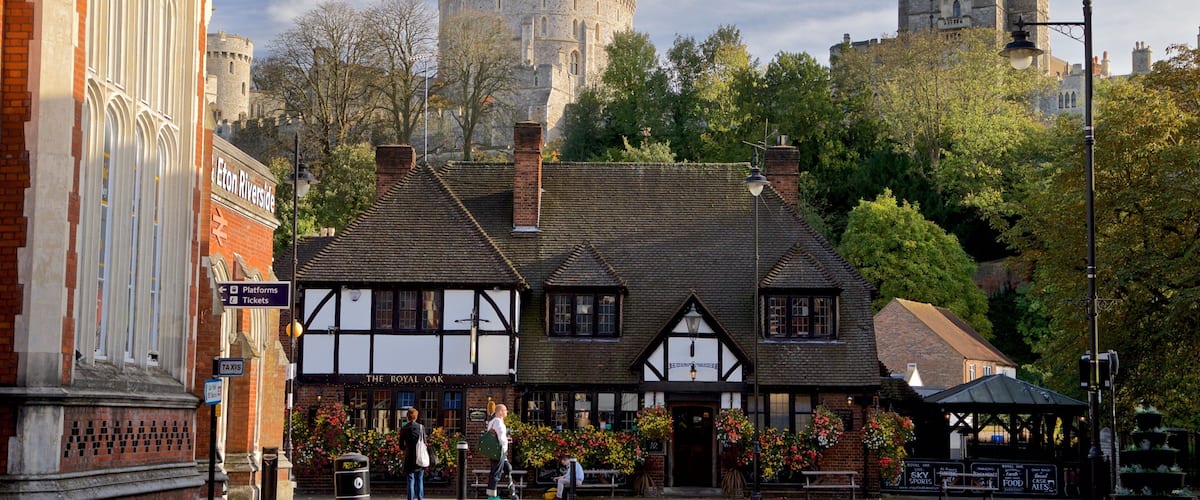Een historisch gebouw met Tudorensche architectuur, een pub genaamd 'The Royal Oak', en een kasteel op de achtergrond.