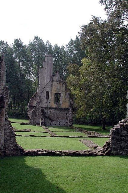 An ancient stone structure surrounded by a grassy field and trees.