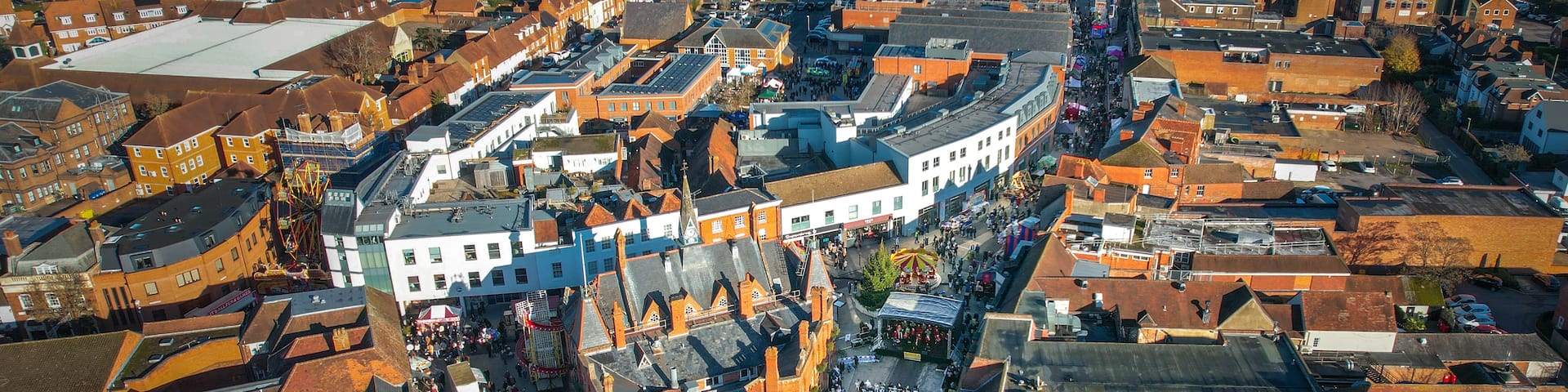 An aerial view of a historic town with narrow streets, traditional buildings, and a central square with a market.