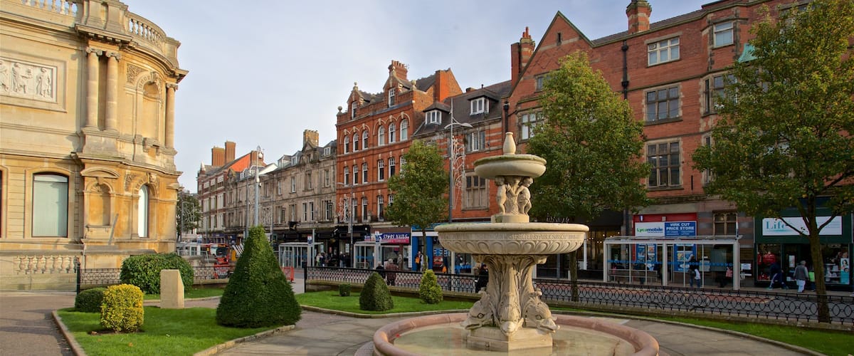 A historic fountain in a square surrounded by classic architecture and a modern building.