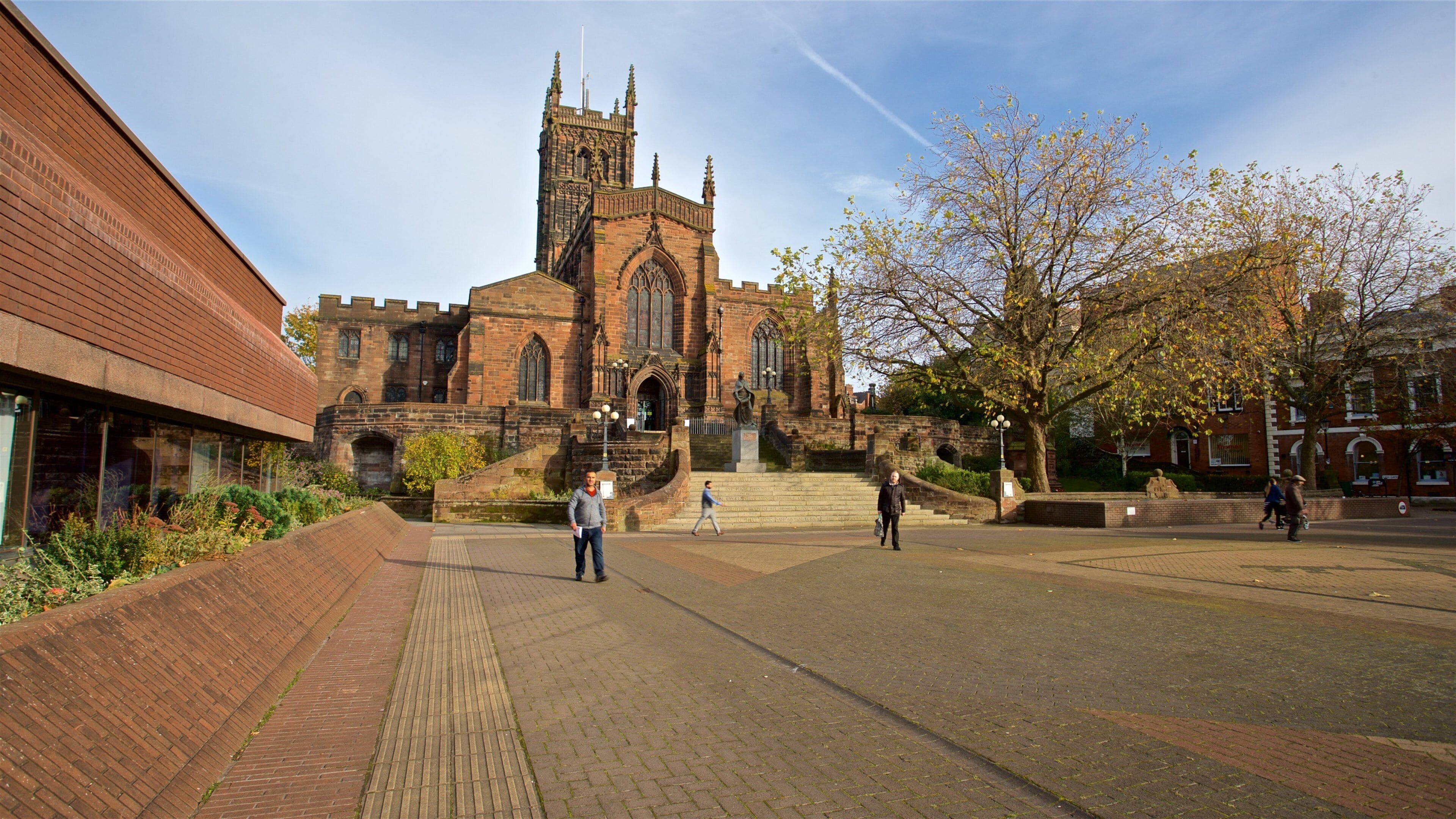 A historic church with a tall tower and a large open plaza.