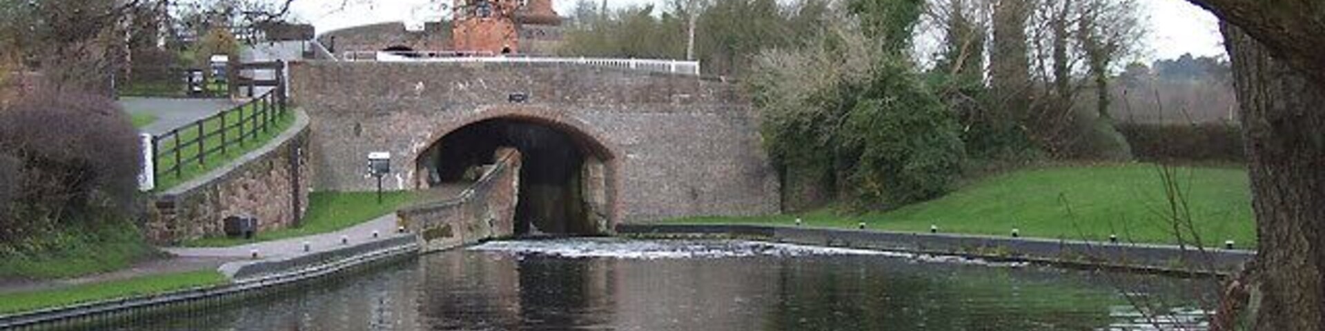 Bratch Bridge (No 47), Staffordshire and Worcestershire Canal The three locks are beyond the bridge. The canal was built wide here to accommodate many waiting boats at busy times. Now a convenient public picnic area allows a good view of narrowboats entering the flight.