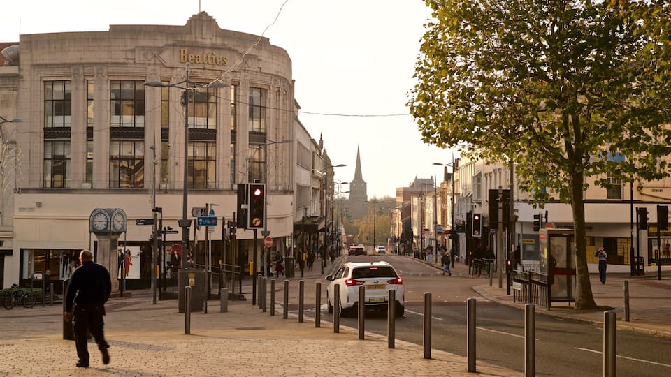 Una strada con un edificio Beatties, una torre dell'orologio e un albero.