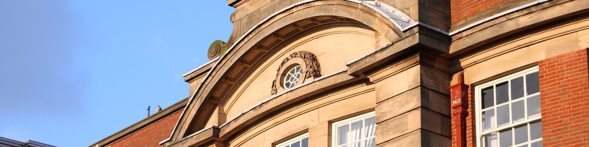 A historic building with a stone facade, large windows, and a decorative archway.