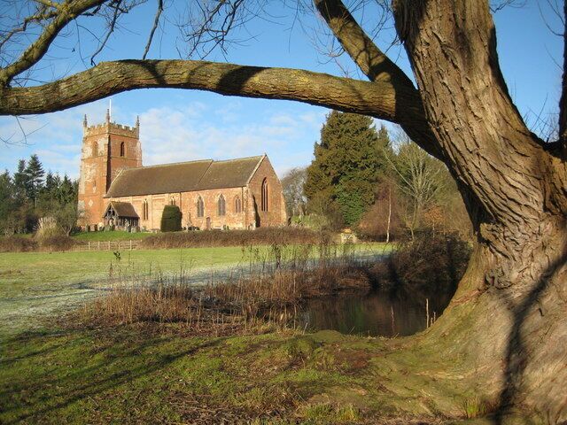 A church with a tower and a large tree in the foreground.