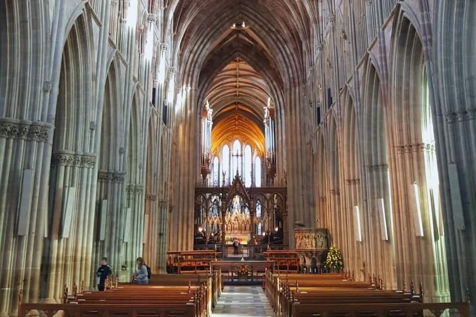 L’intérieur d’une cathédrale, avec de hauts plafonds en voûte, des fenêtres en arc de cercle et des rangées de bancs.