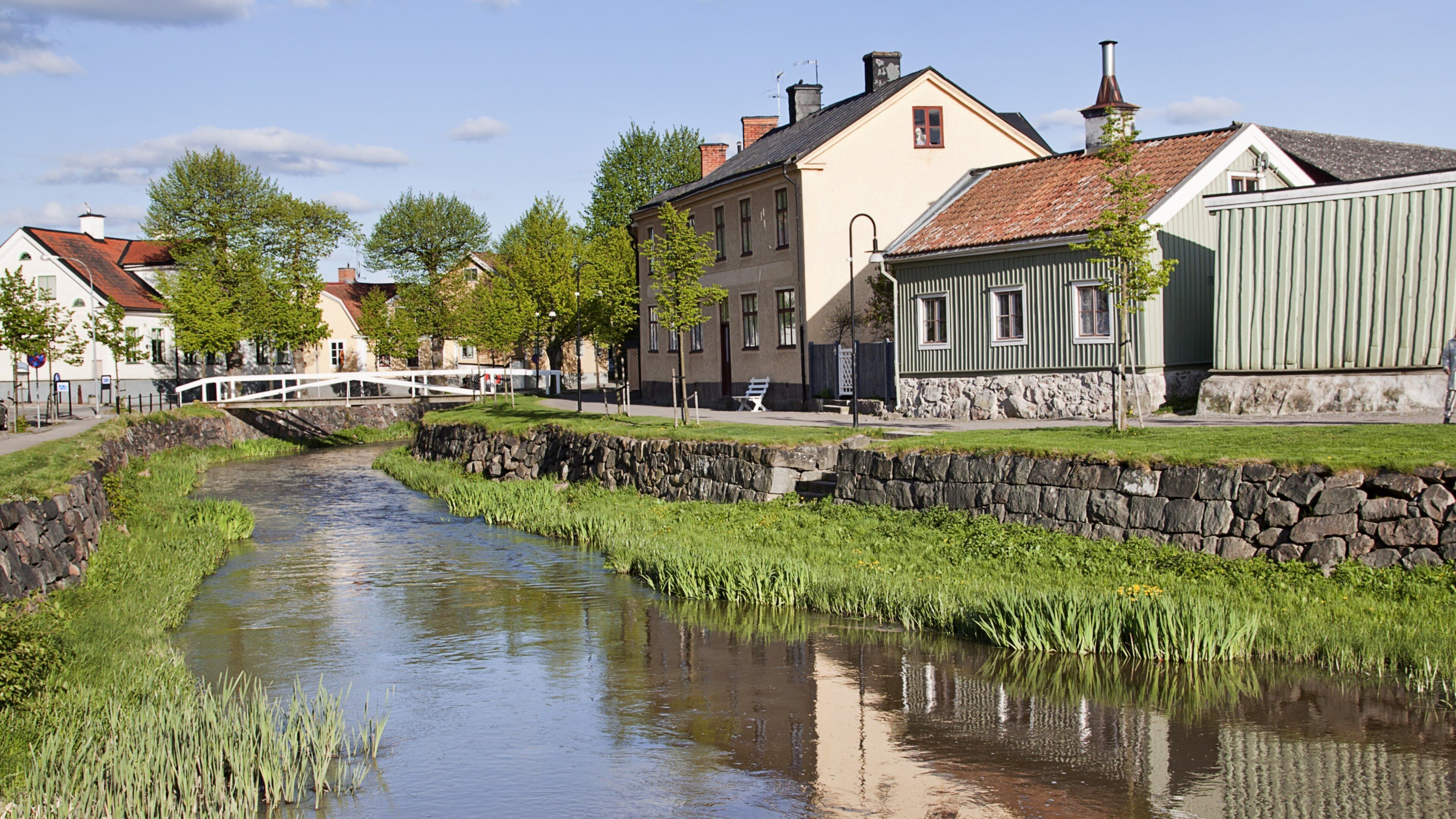 A canal with stone walls, a bridge, and buildings along the water.