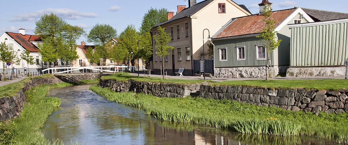 A canal with stone walls, a bridge, and buildings along the water.
