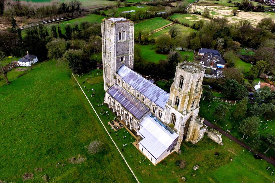 An aerial view of a historic church with a tall tower and a large cemetery.