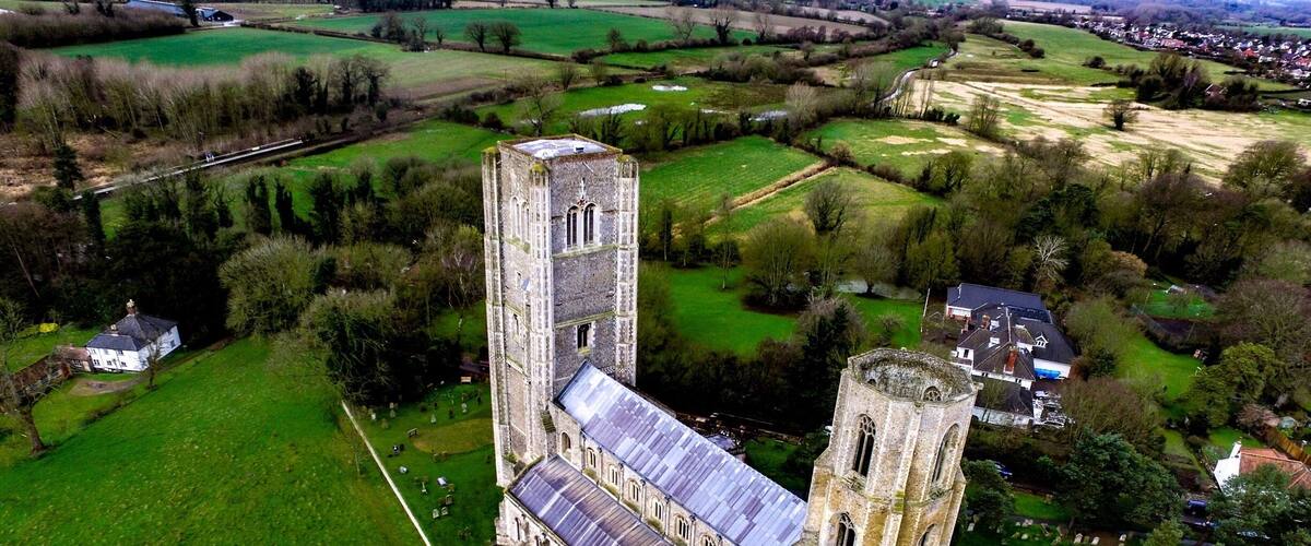 An aerial view of a historic church with a tall tower and a large cemetery.