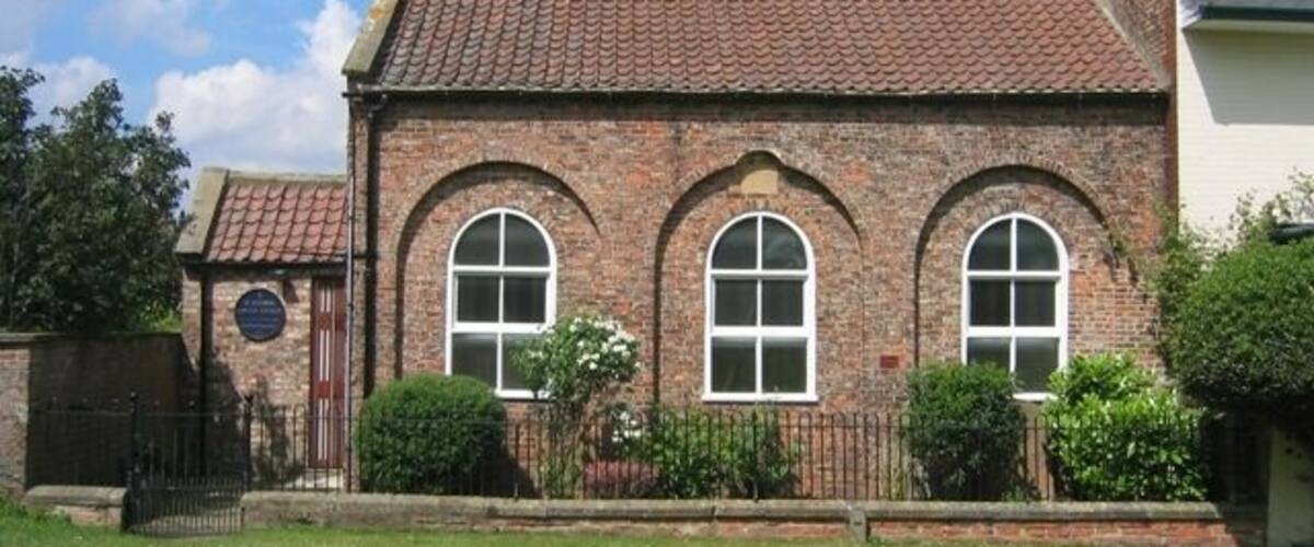 A brick building with a tiled roof and three arched windows.