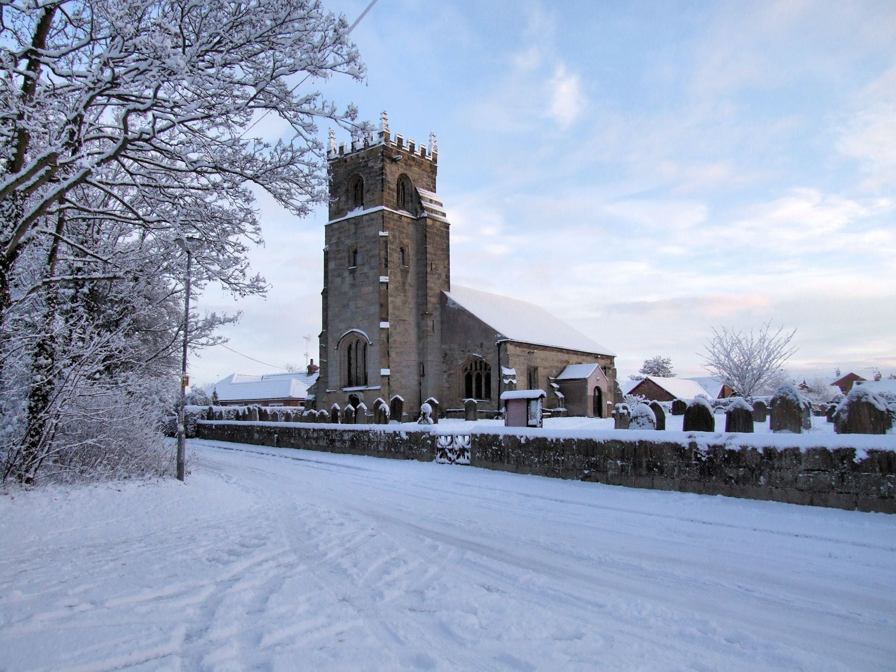A snow-covered church with a tall tower and arched windows.