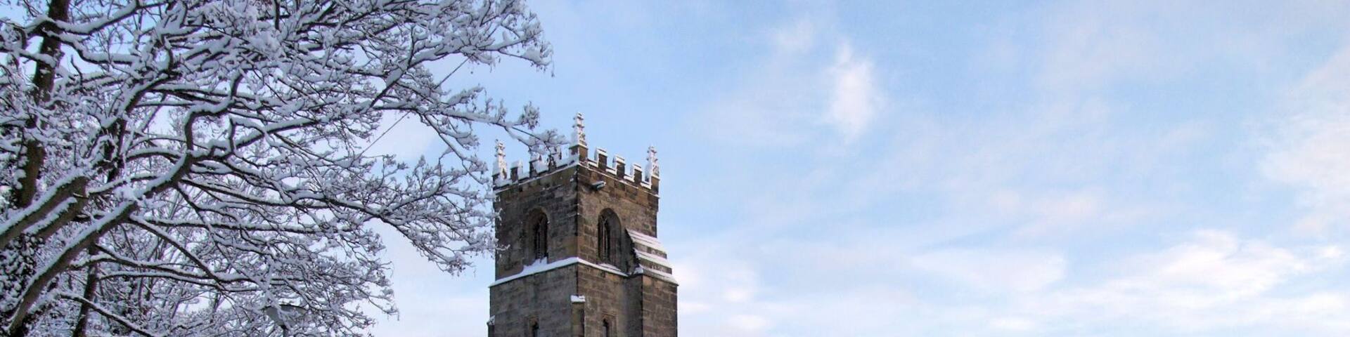 A snow-covered church with a tall tower and arched windows.