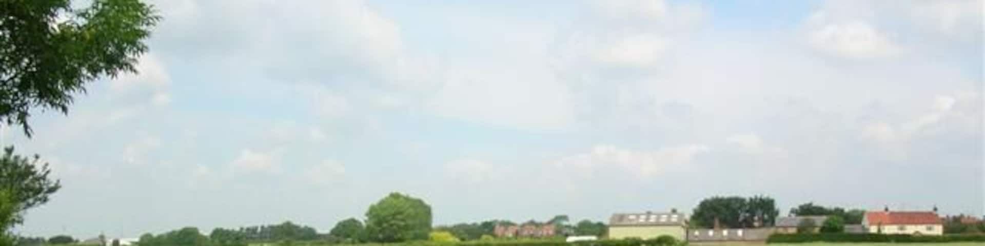 The view towards Shipton. A field with a hedgerow of poppies, and behind, Skelton.