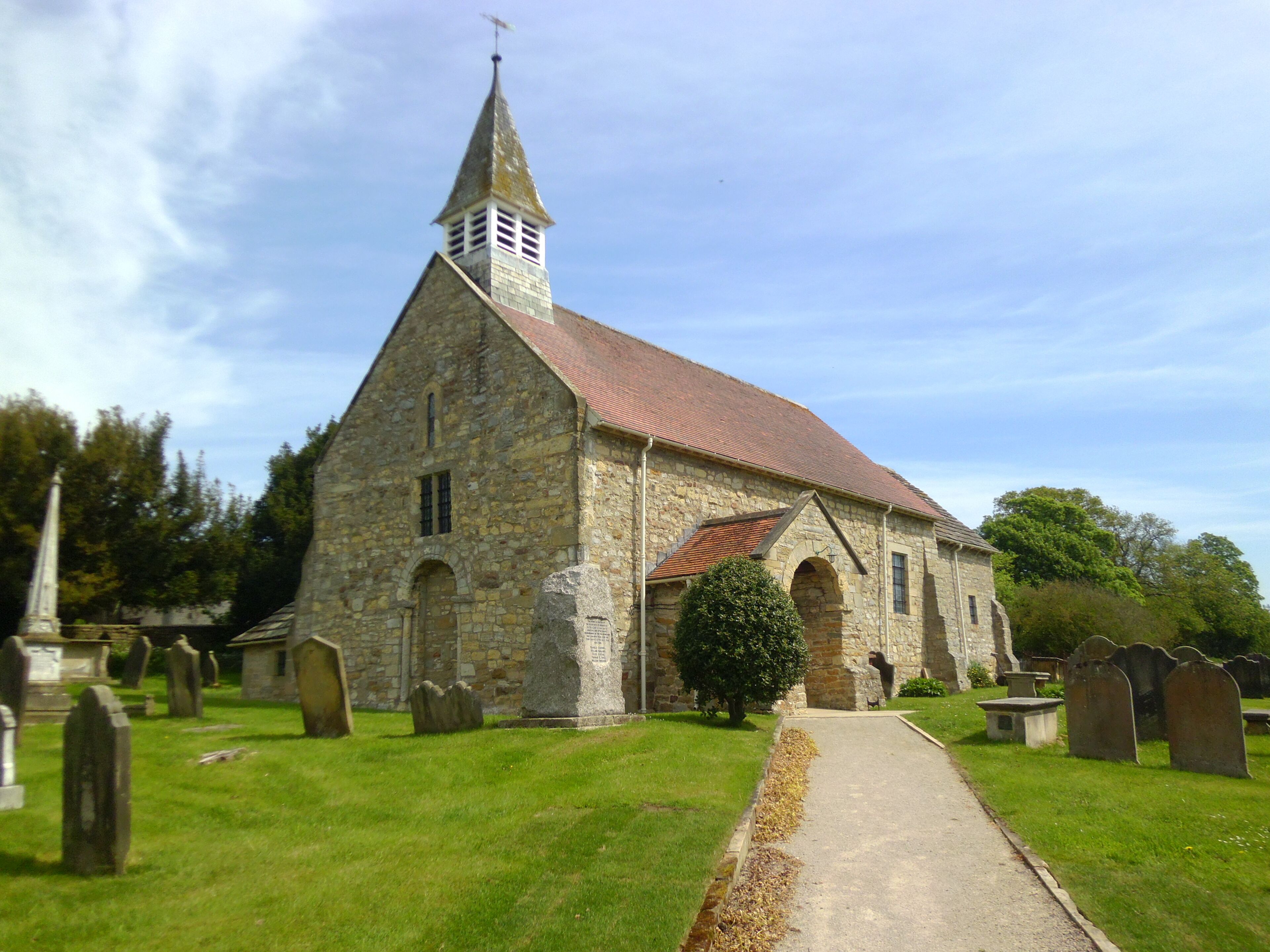 A stone church with a red roof and a steeple.