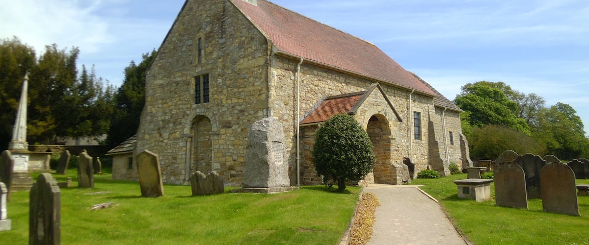 A stone church with a red roof and a steeple.