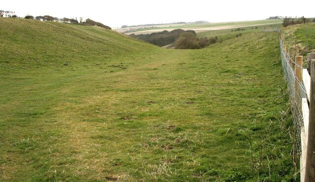 A grassy hill with a fence on the right.