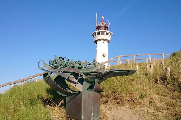 Un phare, une sculpture en métal et une clôture en bois.