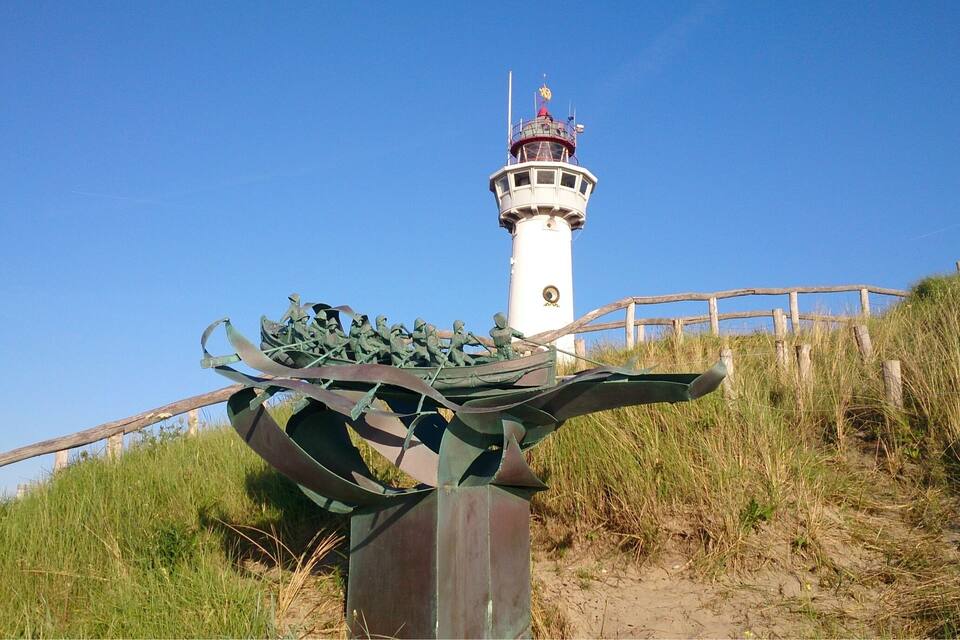 A lighthouse, a metal sculpture, and a wooden fence.