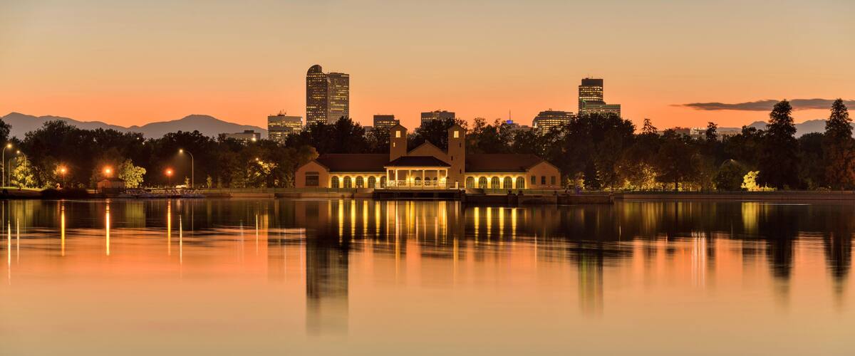 City Park at Dusk - A colorful Autumn dusk view of Ferril Lake in Denver City Park, with front range mountains and landmark skyscrapers in background, at east-side of Downtown Denver, Colorado, USA.