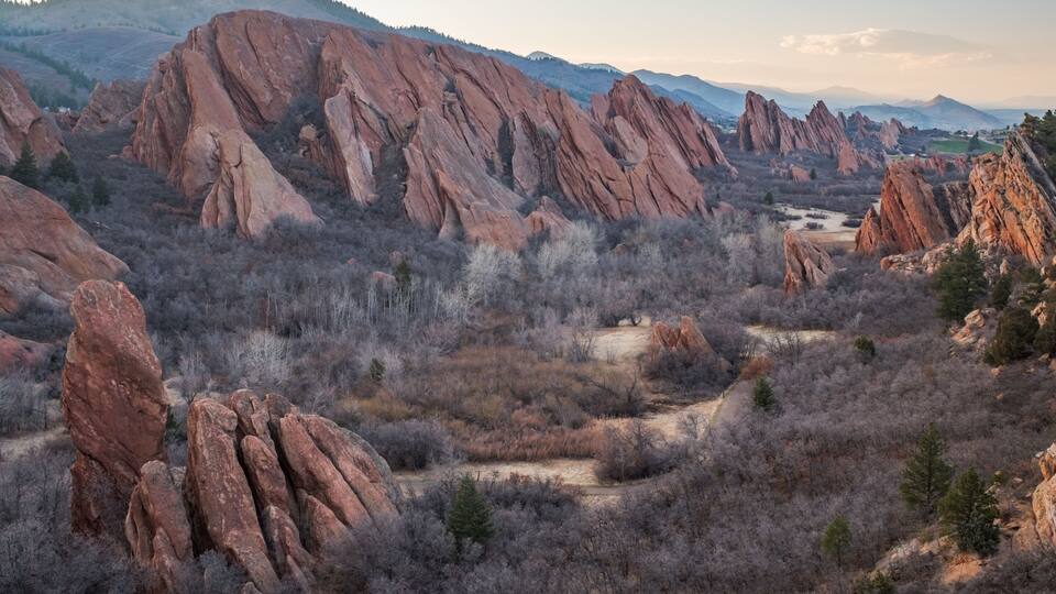 Un paisaje con formaciones rocosas rojas destacadas y un camino de tierra.