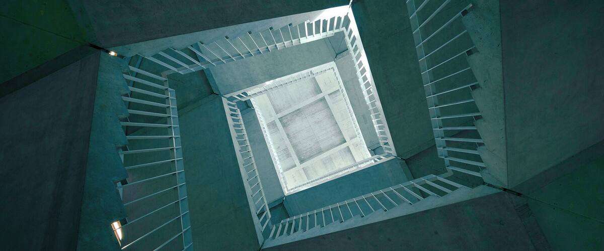 A spiral staircase in a modern building with a glass floor.