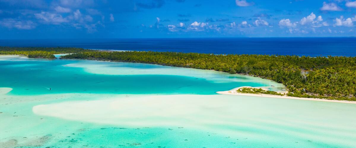A turquoise lagoon, a sandy beach, and a dense forest.