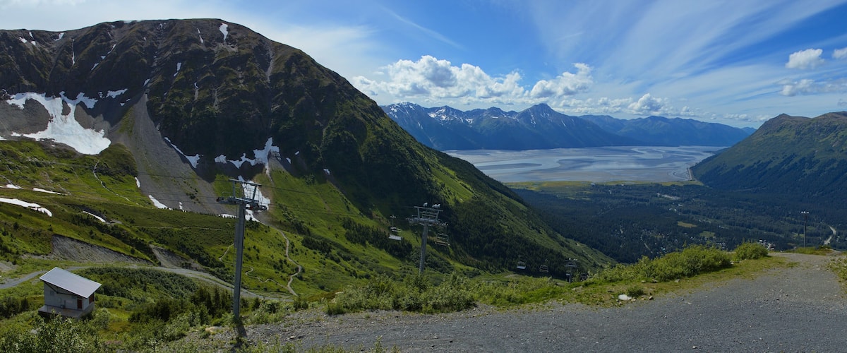 A mountain landscape with a ski lift, a valley, and a lake.