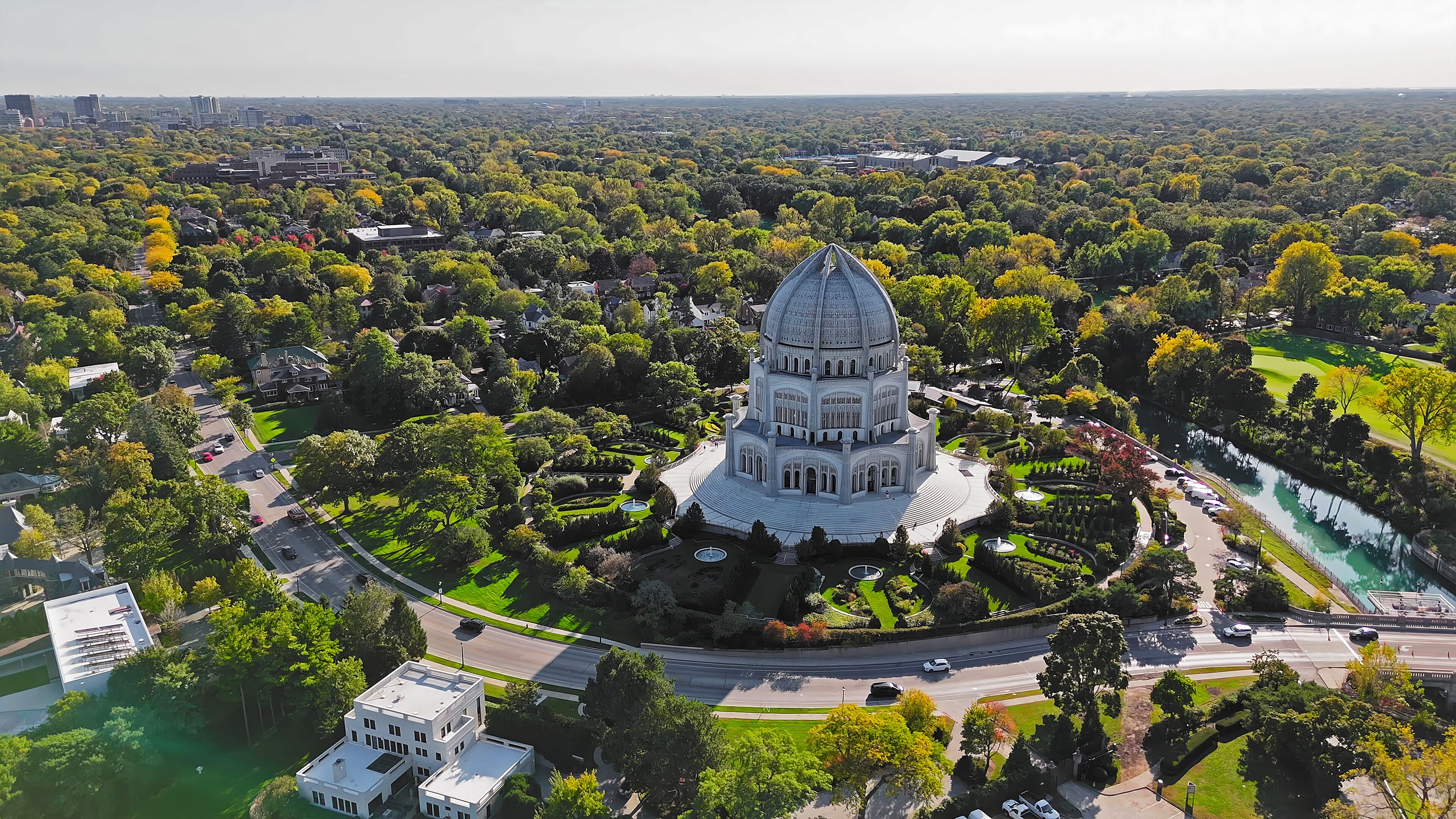Aerial View of Baha'i House of Worship in Illinois. High-angle aerial view of the Baha'i House of Worship in Wilmette, Illinois, surrounded by lush greenery, gardens, and urban landscape.