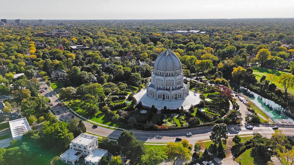 An aerial view of a city with a prominent domed building surrounded by lush greenery and a river.