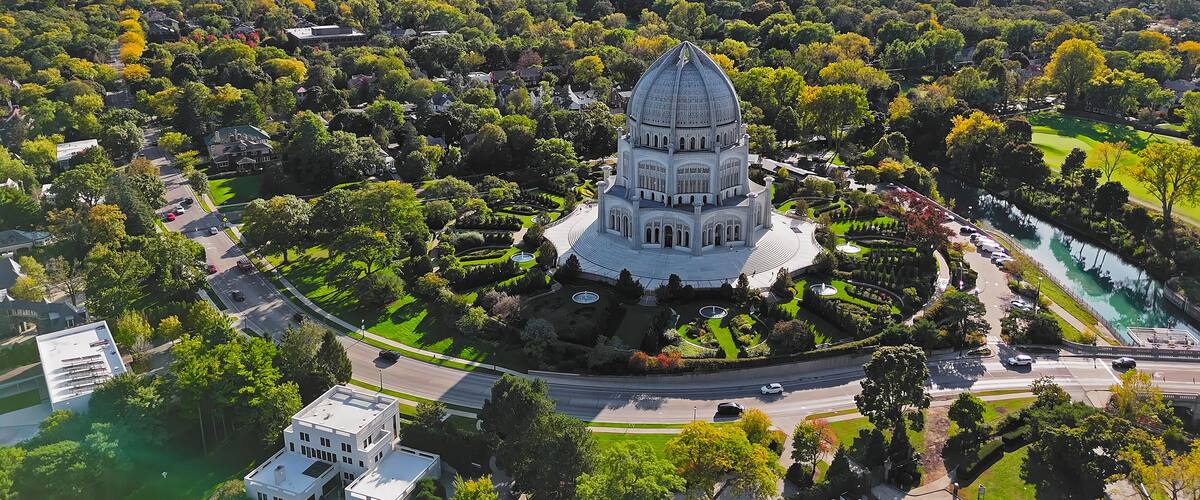 An aerial view of a city with a prominent domed building surrounded by lush greenery and a river.