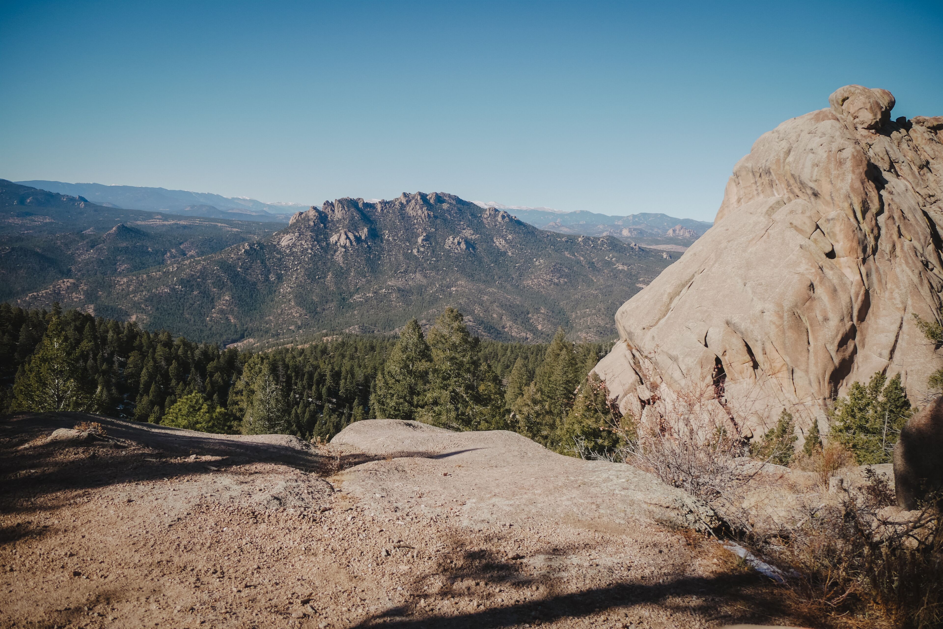 A mountainous landscape with a prominent rocky outcrop and dense forested areas.