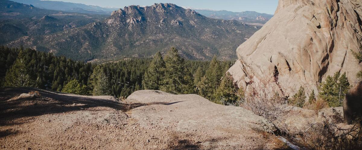A mountainous landscape with a prominent rocky outcrop and dense forested areas.