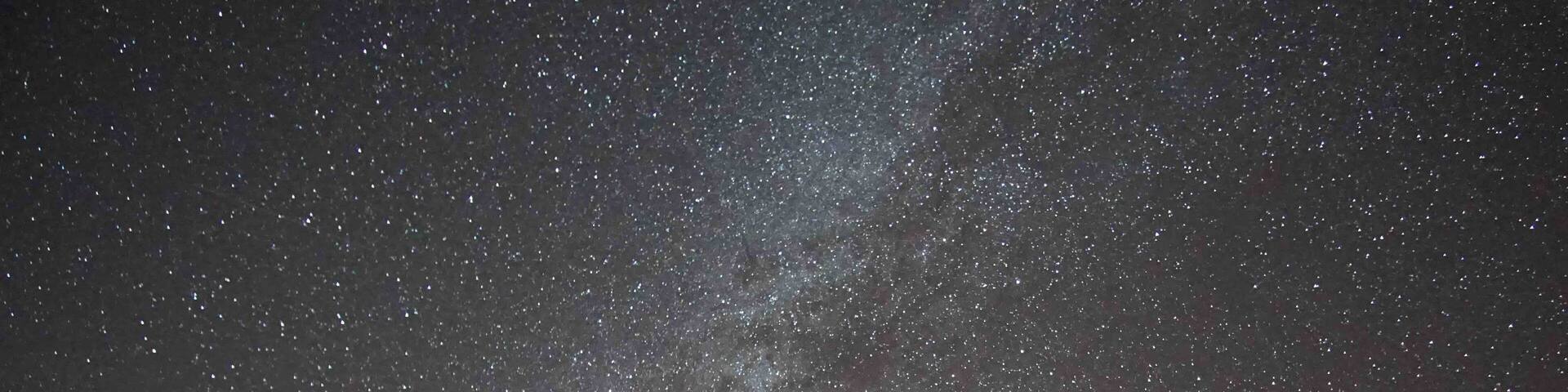 A starry night sky with a vintage truck parked in a desert landscape.