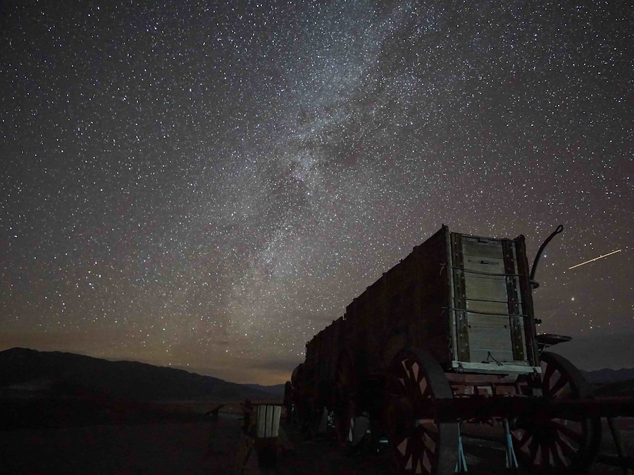 A starry night sky with a vintage truck parked in a desert landscape.