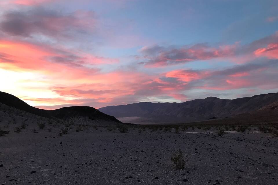 A desert landscape with mountains in the background and a colorful sky.