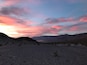 Paisaje desértico con montañas al fondo y un cielo colorido.