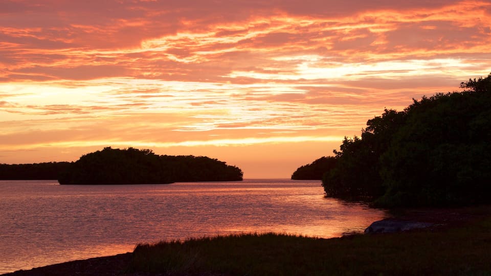 A sunset over a body of water with two islands silhouetted against the sky.