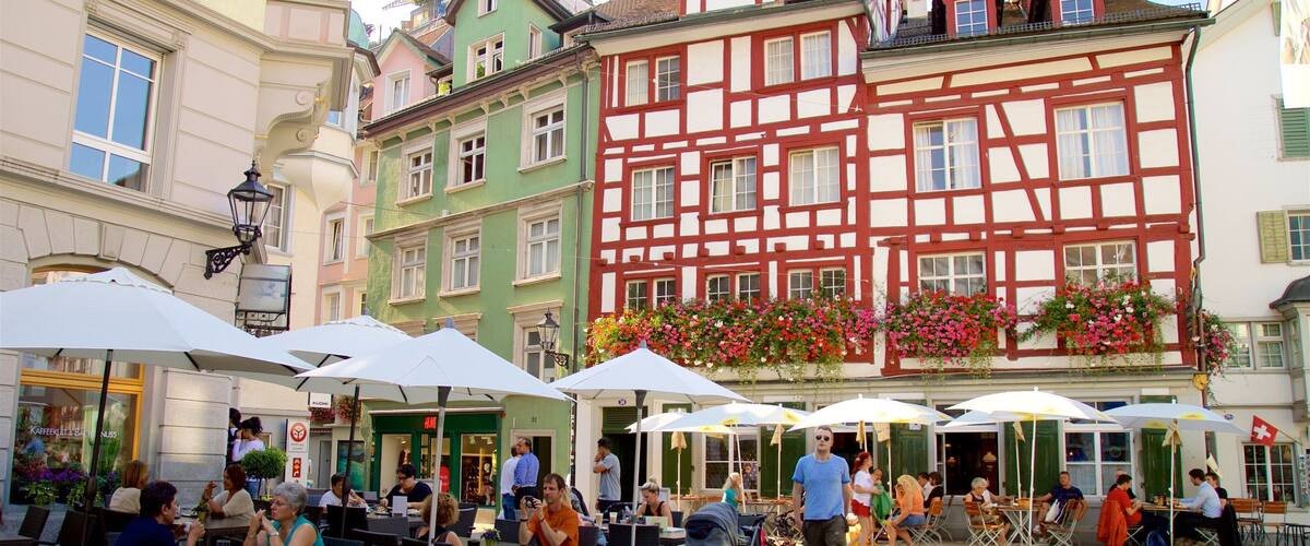 Eine europäische Straße mit bunten Fachwerkhäusern, Straßencafés und Menschen, die dort essen.