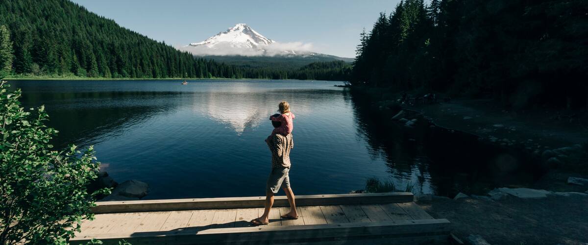 A father carries his daughter on his shoulders at Trillium Lake, OR.