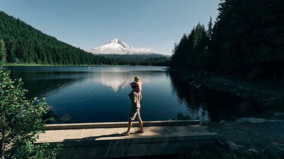 A father carries his daughter on his shoulders at Trillium Lake, OR.