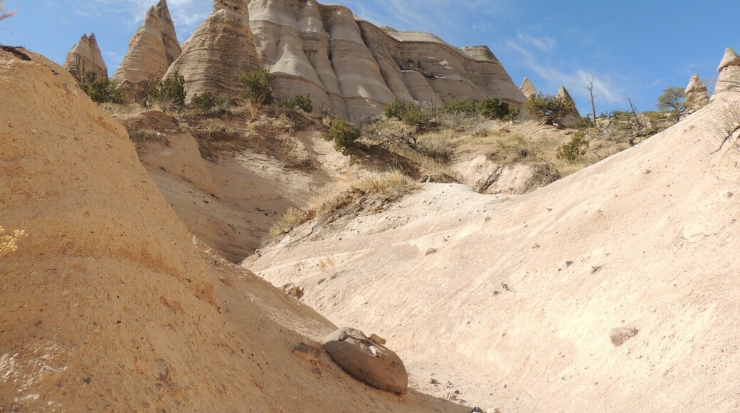 New Mexico’s stunning Kasha-Katuwe Tent Rock formations are the product of volcanic eruptions 6 to 7 million years ago. Many of the pumice, ash and tuff deposits are over 1,000 feet thick. Tremendous explosions from the Jemez volcanic field spewed pyroclasts (rock fragments), while searing hot gases blasted down slopes in an incandescent avalanche called a “pyroclastic flow.”
Over time, wind and water cut into these deposits creating canyons and arroyos, scooping holes in the rock and contouring the ends of small, inward ravines into smooth semi-circles.
Two hiking trails (the Cave Loop Trail and the Canyon Trail) allow visitors amazing access to this National Monument. We hiked the tougher Canyon Trail, a 1.5 mile trek up a narrow canyon involving a 630-foot climb to the mesa top, driven by the promise of fantastic views of the Sangre de Cristo, Jemez, and Sandia mountains, as well as the Rio Grande Valley. We were not disappointed.
Be sure to arrive early in the day (the monument opens at 8 am during winter months, 7 am during the summer) to avoid the crowds and the heat. Bring plenty of water; the monument has no concessions, but does offer the basics in terms of facilities. The nominal $5 fee per vehicle is returned to the site for monitoring, maintenance, and improvements.
See more pictures and commentary via my blog at http://www.aplacecalledroam.com/home/hiking-the-stunning-kasha-katuwe-tent-rocks-national-monument .
