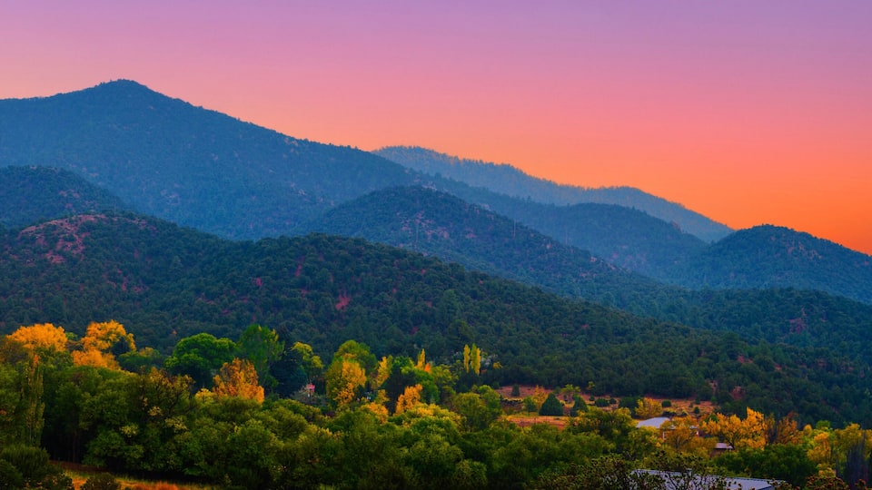 A mountainous landscape with dense forests and a clear sky.