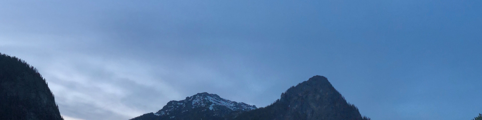 Une chaîne de montagnes aux sommets enneigés et aux forêts denses.