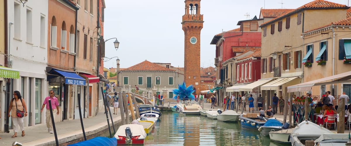 A canal in Venice with boats, buildings, and a clock tower.