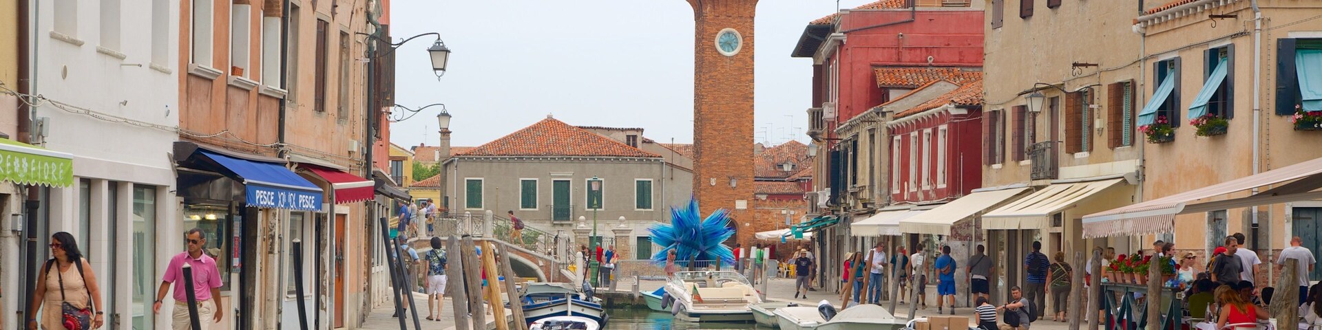 A canal in Venice with boats, buildings, and a clock tower.