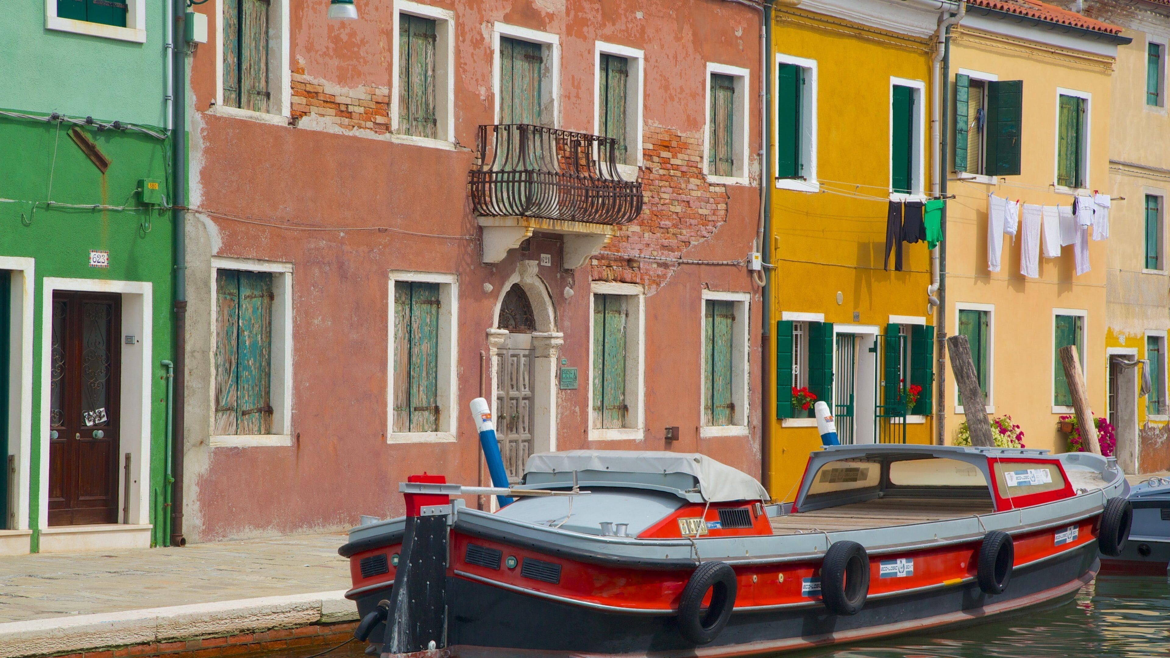 A narrow canal with colorful buildings and a boat docked at the edge.