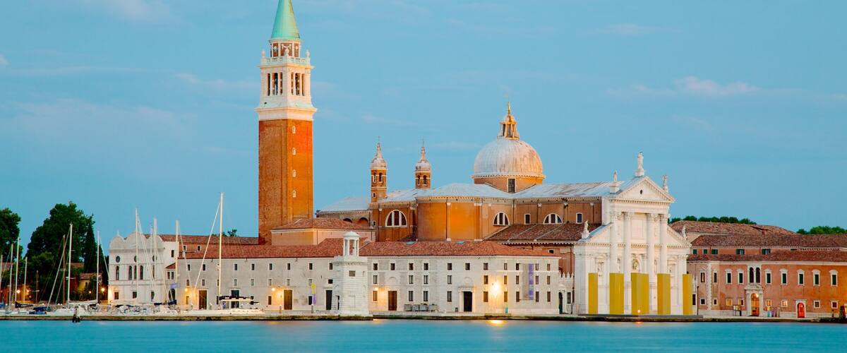 A historic building with a prominent tower and domed roof, situated by a waterfront.
