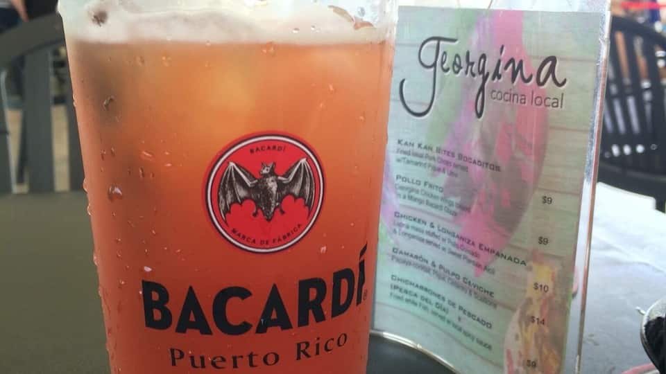 A glass of Bacardi Puerto Rico beer with a black straw, placed on a coaster with a menu in the background.