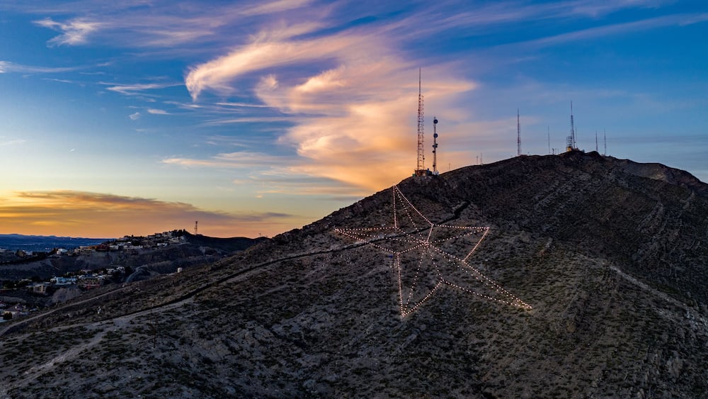 Un paysage montagneux agrémenté d’une installation lumineuse en forme d’étoile et de pylônes de communication.